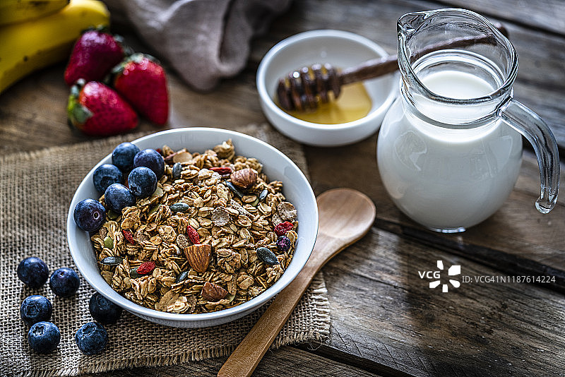 健康早餐:木桌上放有水果、坚果和种子的麦片碗图片素材