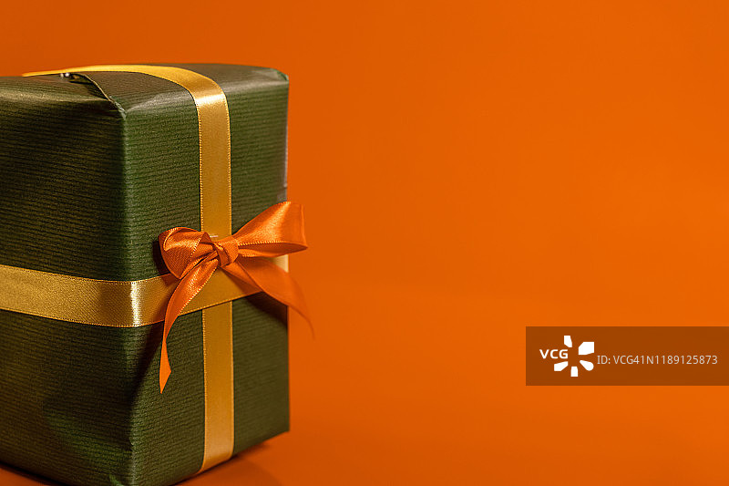 橙色背景上的橙色丝带，绿色礼物图片素材