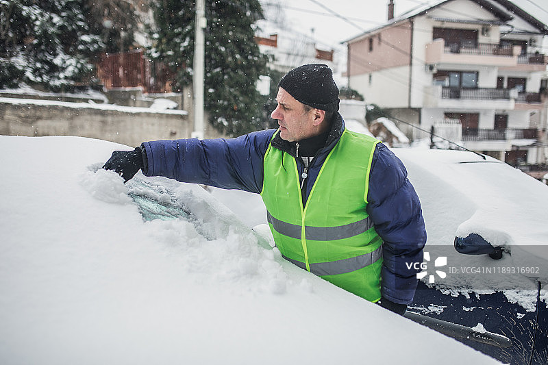 一位老人正在清除车上的积雪图片素材