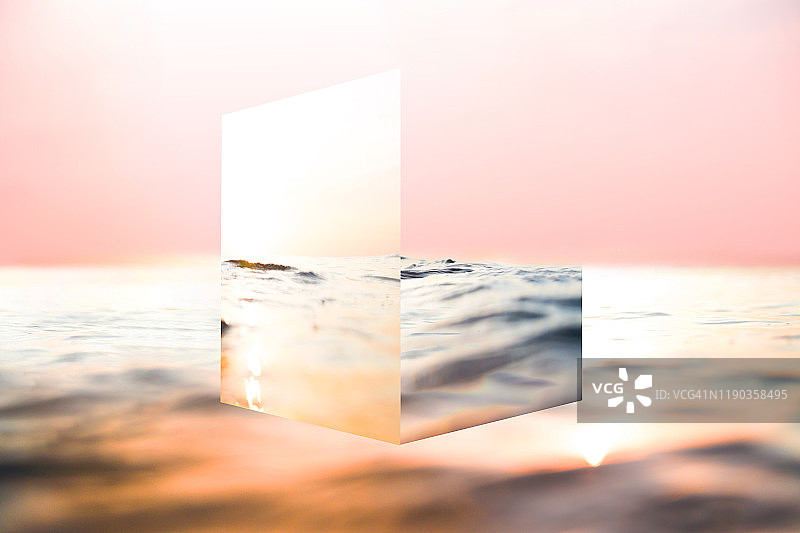 创造性的立方体镜子与大海的倒影和日落的颜色玩。图片素材