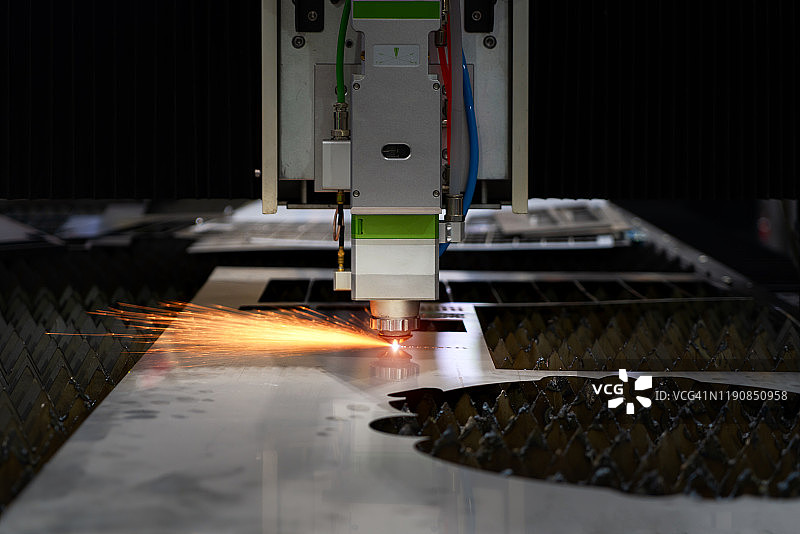 金属工业工厂的光纤激光切割机用火花光切割金属板材。高新技术制造业的概念。图片素材