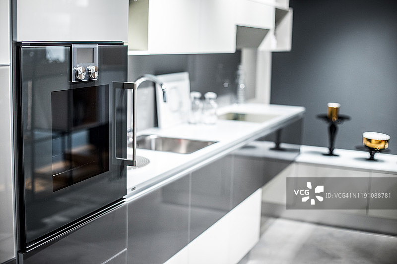 一间现代、简约、外观流畅的厨房，配备了一个模块化的炉子和灰白色的橱柜图片素材