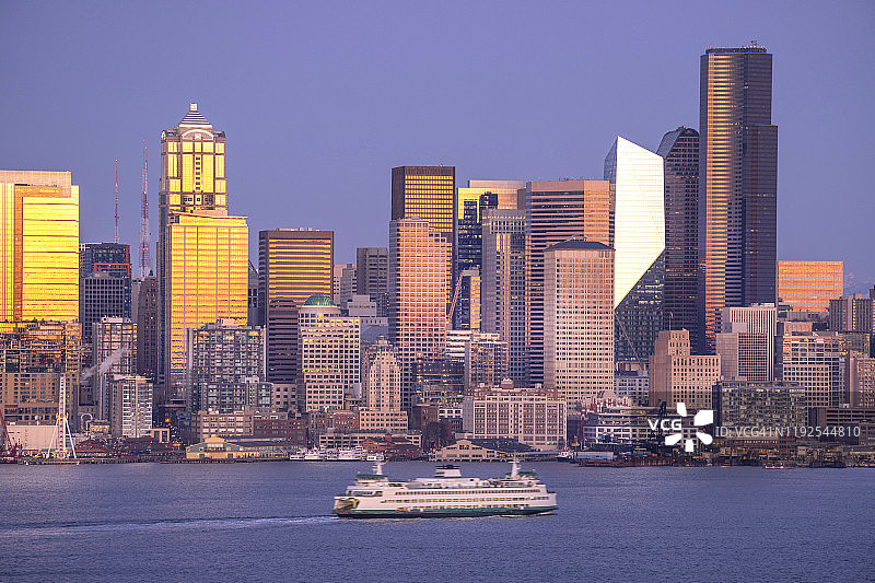 暮色中的西雅图海滨，普吉特湾，渡船和城市天际线，夕阳的余晖反射在办公大楼和摩天大楼。图片素材