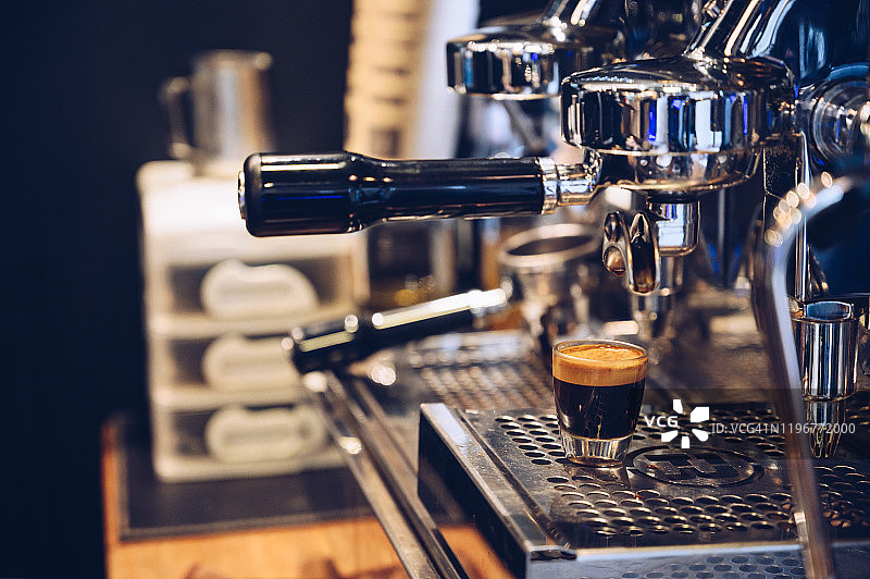 浓缩咖啡从咖啡机倒出来的特写。专业的咖啡酿造。图片素材