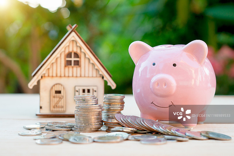 小猪储蓄罐和硬币落在上面用流动资金管理和家的模式是目的地放在公园的木头上，贷款和商业投资与未来的房地产概念。图片素材