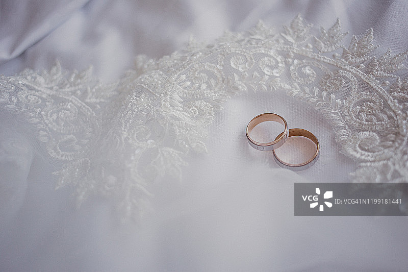 婚姻的概念。金色的结婚戒指戴在白色的面纱上。特写镜头。空间的文本。俯视图图片素材