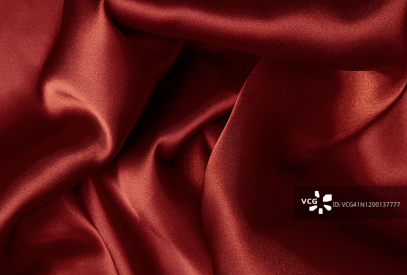 抽象的背景奢侈布。波浪褶皱的红色丝绸纹理缎子天鹅绒材料或豪华的红色丝绸作为背景，红色丝绸织物的褶皱。图片素材