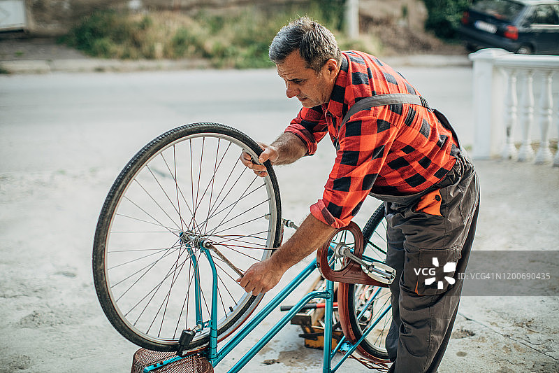 老人独自在前院修自行车图片素材