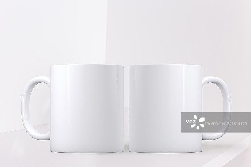 白色的杯子模型。白色背景的架子上放着两只白咖啡杯。完美的商业销售马克杯，只是覆盖您的报价或设计上的形象。图片素材