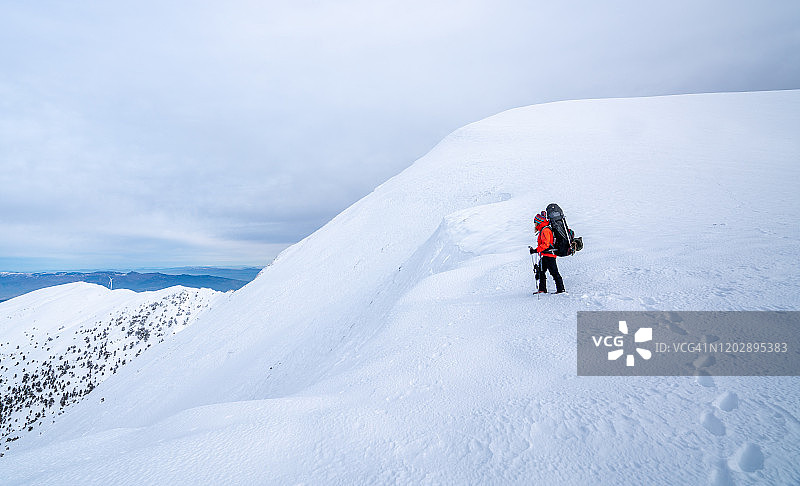 冬季，女性高山攀登者在高海拔的山峰上行走图片素材