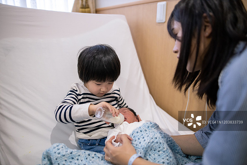小男孩在医院给新生婴儿喂奶图片素材
