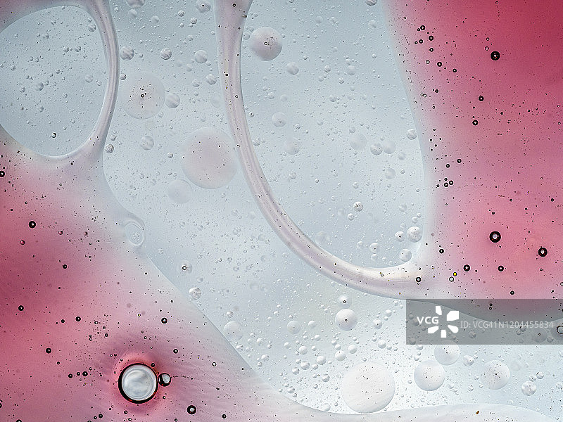 完整的框架抽象的形状和纹理形成的泡沫和滴油渍在粉红色的液体背景。图片素材