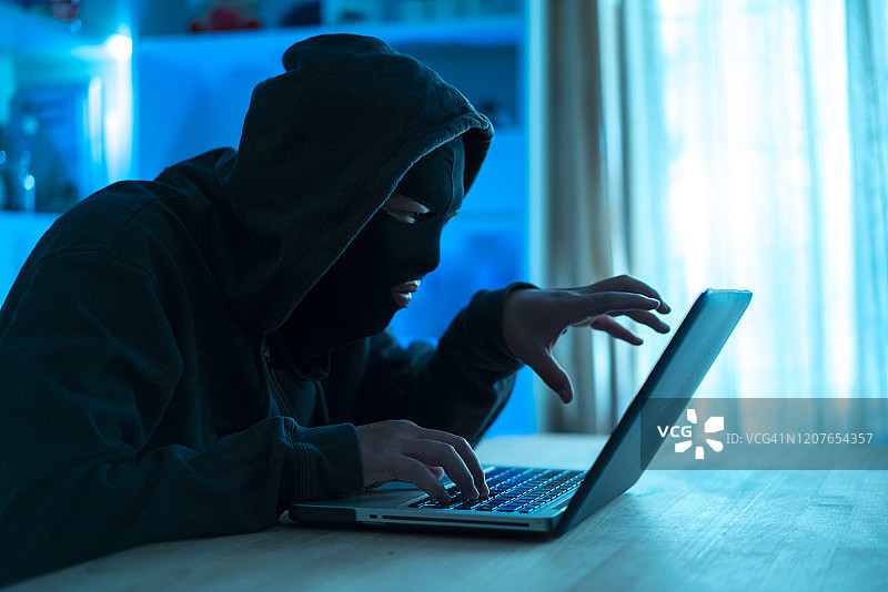 危险的蒙面黑客闯入政府数据服务器和感染他们的系统与病毒。他的藏身处有黑暗气氛图片素材