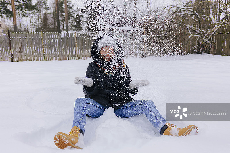快乐的女人坐在雪地上玩雪球图片素材