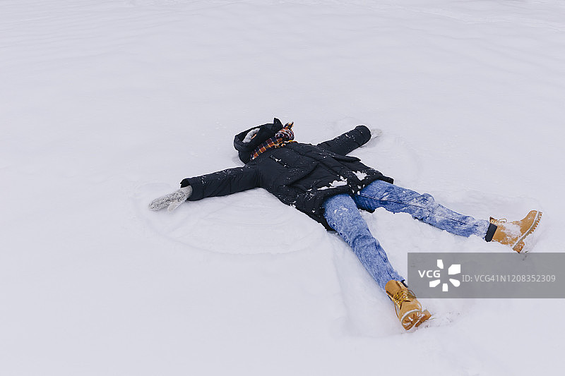女人躺在雪地上做雪天使图片素材