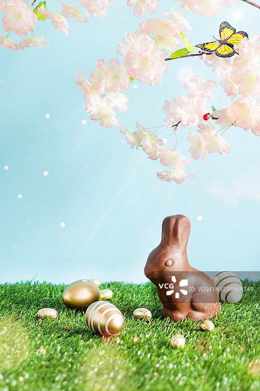 复活节彩蛋，巧克力复活节兔子和盛开的春天的树枝在蓝色的背景。图片素材