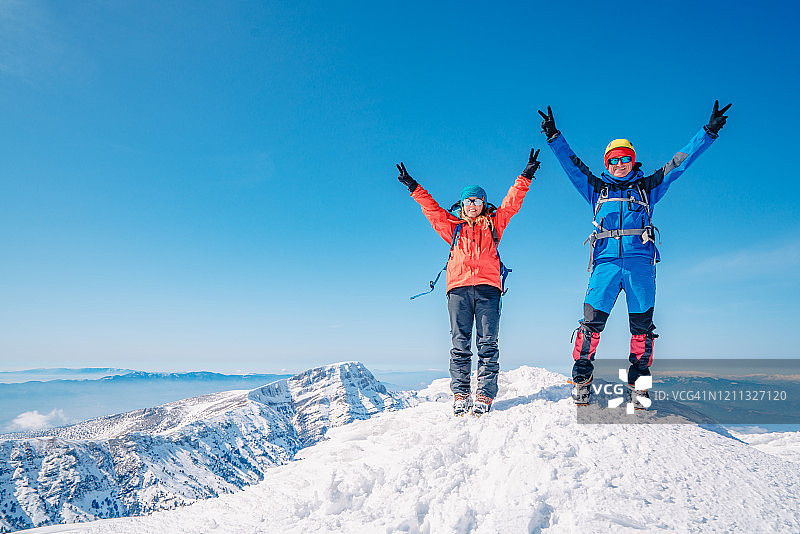 冬天，阿尔卑斯山登山队正在一座高海拔的山峰上做和平手势图片素材