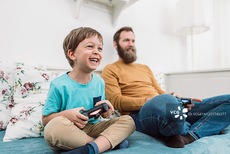小男孩在和他爸爸玩电子游戏图片素材