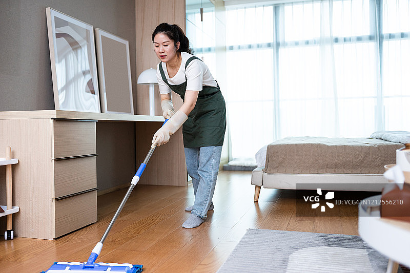 一个女人在用拖把打扫地板图片素材