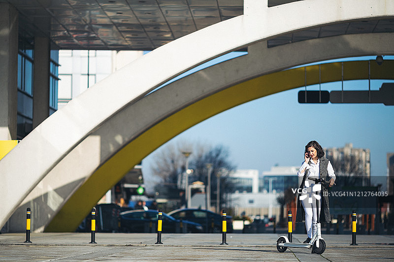 女商人骑着踏板车在城市里图片素材