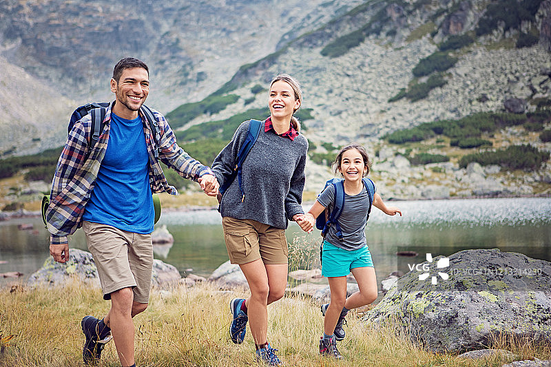 快乐的一家人沿着山湖徒步旅行图片素材