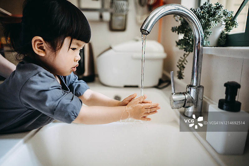 一个亚洲小女孩保持双手卫生，用肥皂在水槽里洗手图片素材