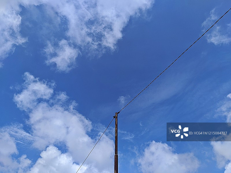 低角度的电力电缆对抗蓝天和云图片素材