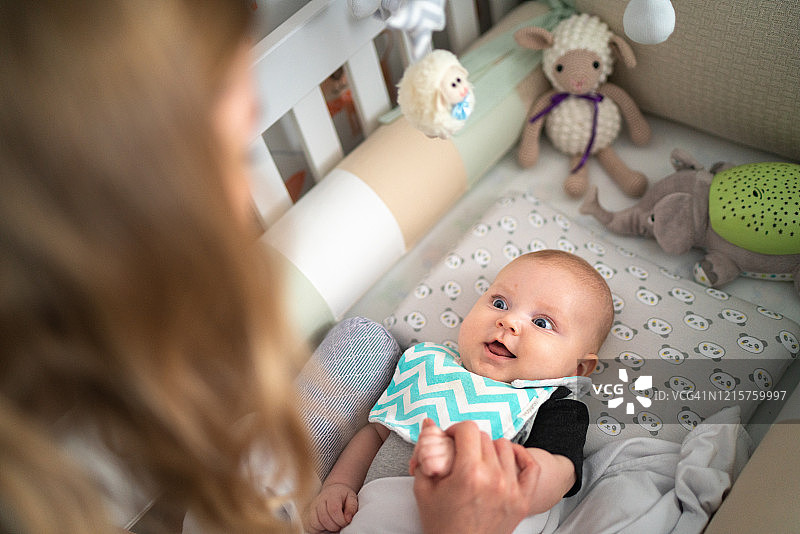 母亲和刚出生的男婴在婴儿床上玩得很开心图片素材