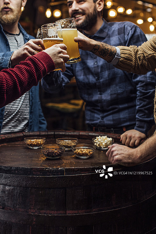 一群男人在酒吧与啤酒干杯，一个近距离图片素材
