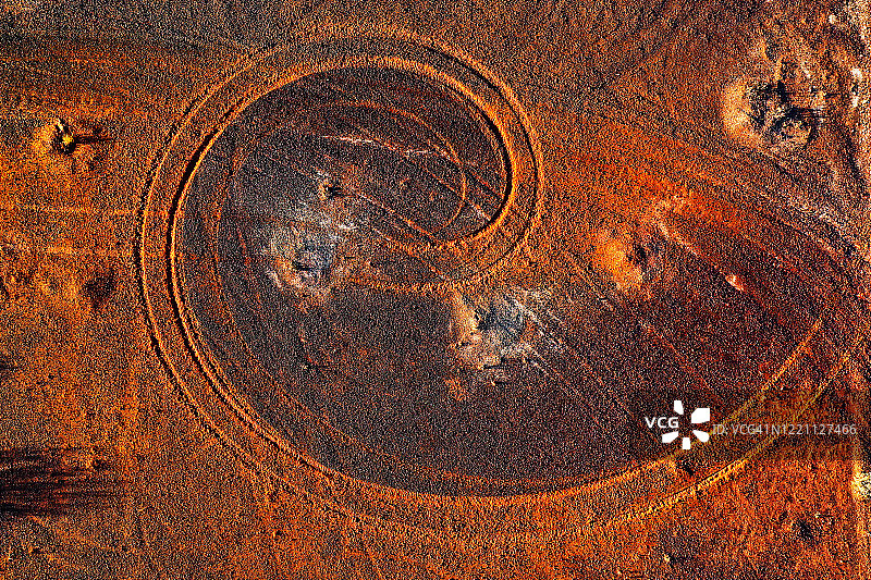 抽象的漩涡图案从汽车轮胎轨道在红土，被黄昏的阳光照亮，偏远的澳大利亚农村图片素材