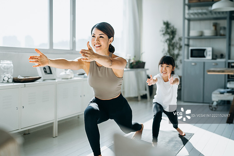 快乐的年轻亚洲母亲和小女儿一起锻炼和练习瑜伽在家里图片素材