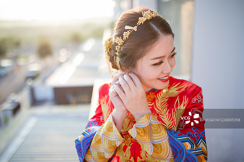 一位亚洲华人新娘正在准备她的婚礼。她穿着中式的婚纱。图片素材