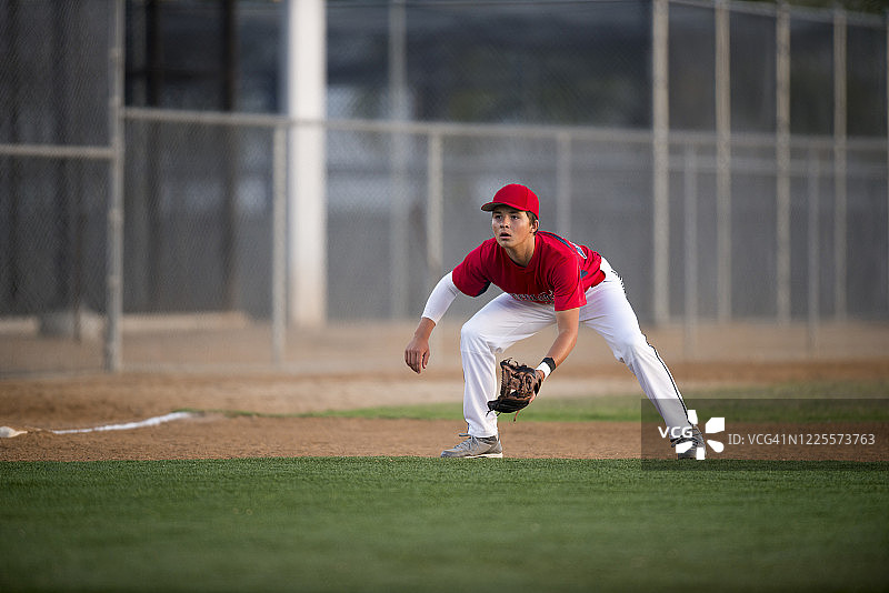 穿着红色制服的青少年棒球运动员准备打滚地球图片素材