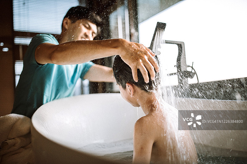 男孩和他的父亲在浴缸里享受泡泡浴图片素材