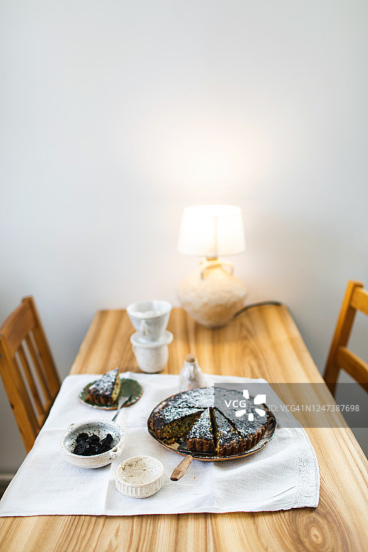 漂亮风格的木制餐桌为早餐设置。天然有机早餐，新鲜烘焙的蛋糕，干果，果酱，咖啡，牛奶壶，亚麻桌布和陶瓷餐具。关闭了。图片素材