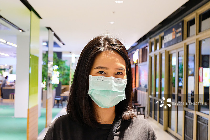 成年亚洲妇女戴着外科口罩在百货商店购物。我们需要新的正常的、新的行为生活方式来保护我们的健康免受冠状病毒的侵害。保持安全和社交距离。图片素材