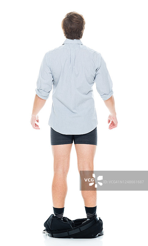白人男性穿着衬衫在白色背景前脱下裤子图片素材