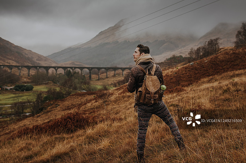 一个年轻人站在苏格兰高地的格伦芬南高架桥前图片素材