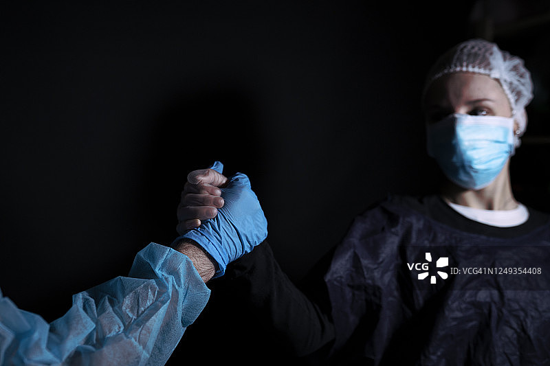 医生和护士穿着防护服握手。图片素材