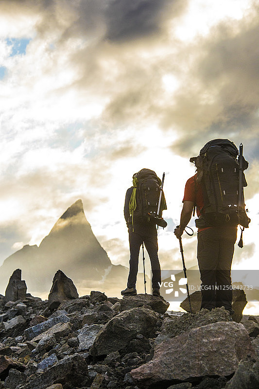 两名登山者向巴芬岛洛基山徒步旅行的后视图。图片素材