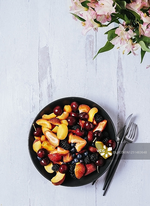一碗新鲜的水果放在白色的木质背景上图片素材