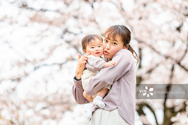 妈妈在樱花树前抱着她的小宝宝图片素材