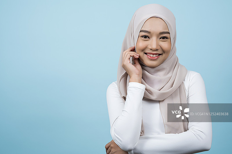 漂亮的亚洲穆斯林妇女戴头巾的肖像。她看起来很时髦，开朗，机敏。工作室拍摄的穆斯林人的概念。图片素材