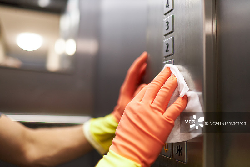 一名女子和一名男子戴着橡胶手套用消毒湿巾消毒和清洁电梯的不同照片图片素材