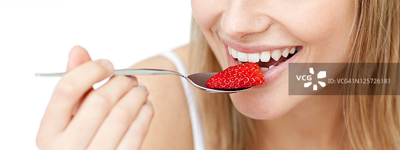 一个微笑着吃草莓的女人的特写图片素材
