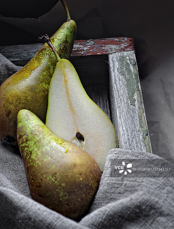 食物摄影新鲜的绿色梨整体和切在木盒侧面的乡村风格的灰色纹理背景近景图片素材