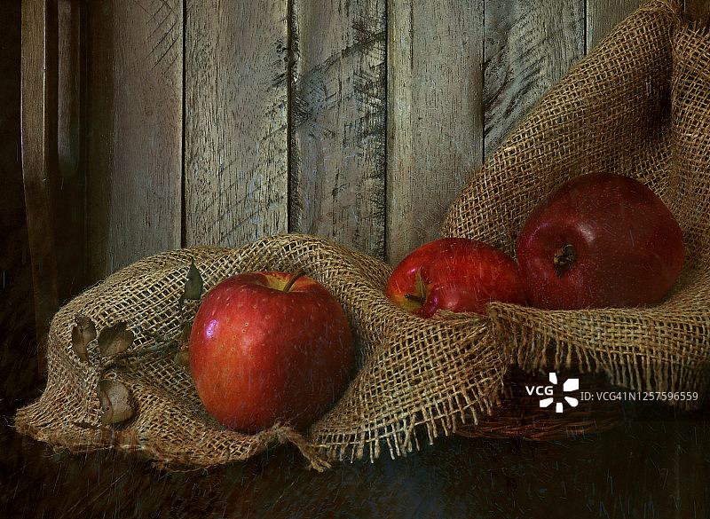 质朴的静物图像与三个苹果在棕色黄麻织物上，以谷仓木材为背景图片素材
