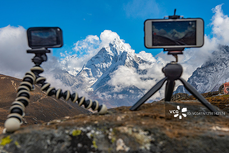移动相机和智能手机设置在三脚架上，以捕捉尼泊尔ama Dablam山的美丽风景。图片素材