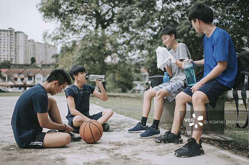 一群十几岁的亚洲华人男孩在放学后在篮球场上打篮球和练习篮球后休息和休息图片素材
