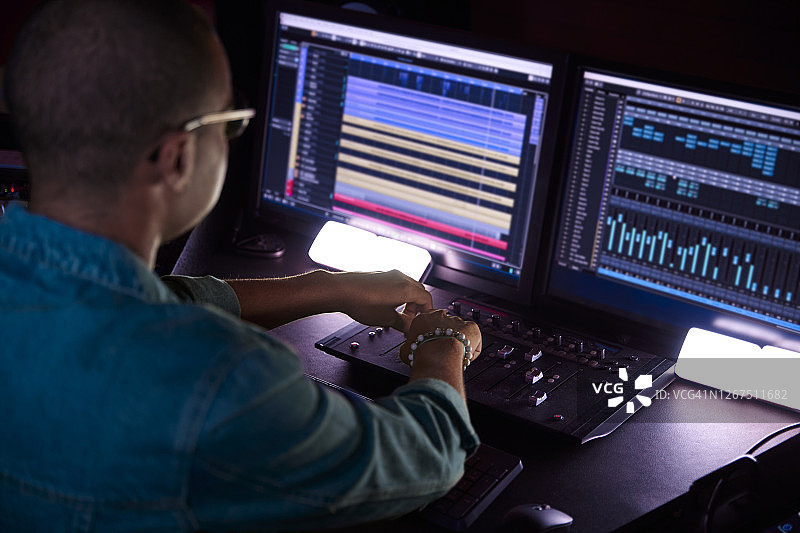 非裔美国制作人工作在音乐工作室的声音混音控制面板上的音乐轨道图片素材